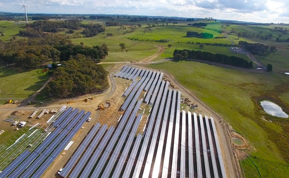 This is an aerial photograph of the Gullen Range solar farm that was being completed by Monford Group. The huge farm and large panels are in the middle of a big green field with rolling hills in the background.