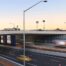 This is a photograph of the major project overpass over the freeway that Monford Group completed. The cars traveling underneath are blurred from the speed they are traveling. Artwork decorates the sides of the large infrastructure..