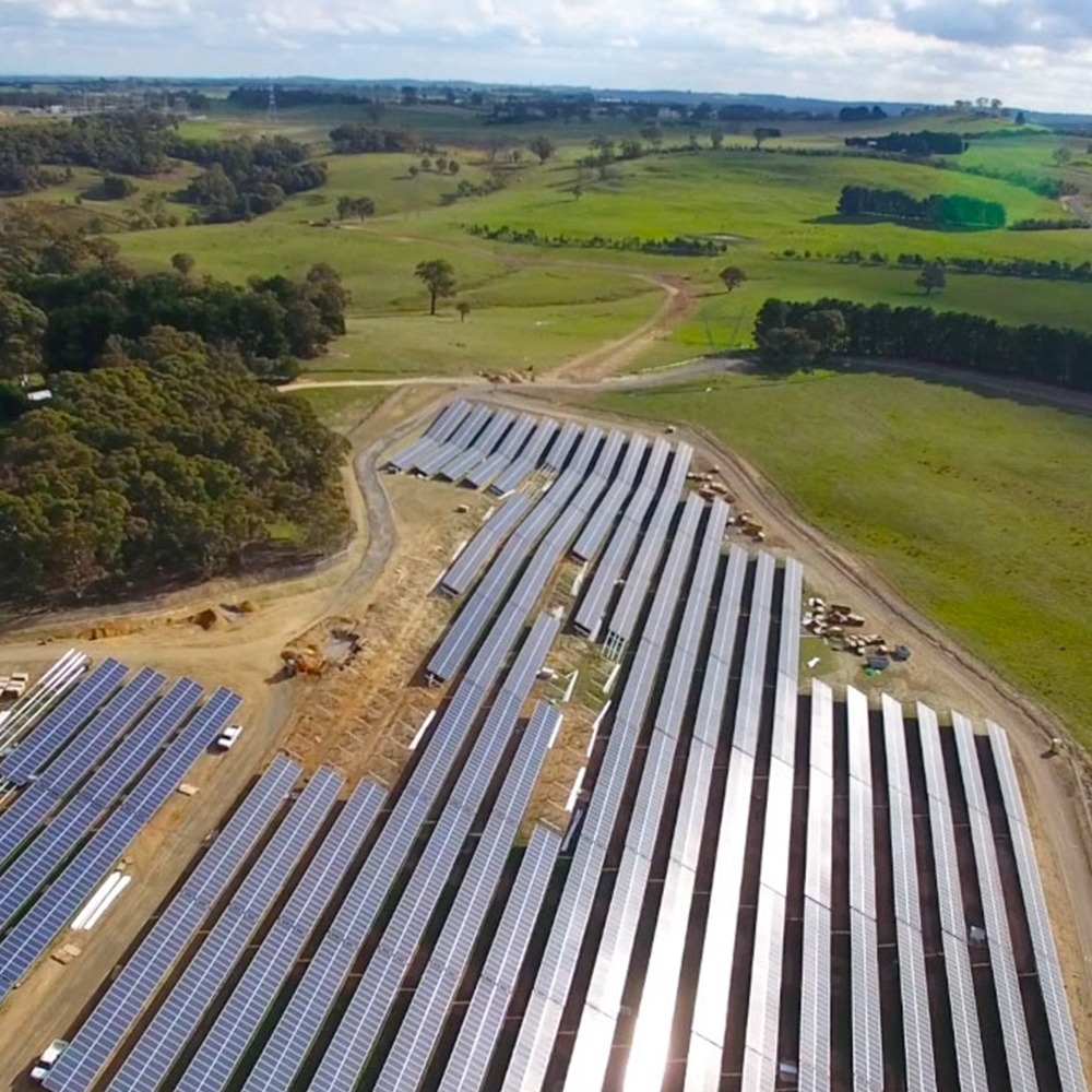 This is an aerial photograph of the Gullen Range solar farm that was being completed by Monford Group. The huge farm and large panels are in the middle of a big green field with rolling hills in the background.